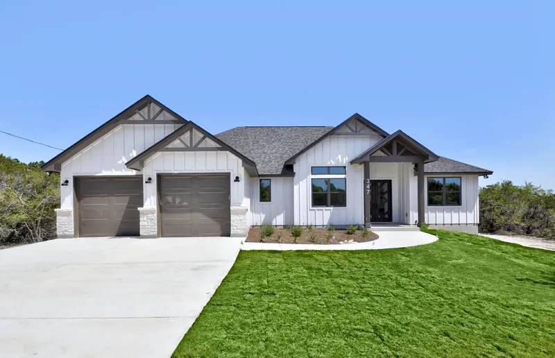 Single-story Hill Country farmhouse with a three-car garage and stone drive