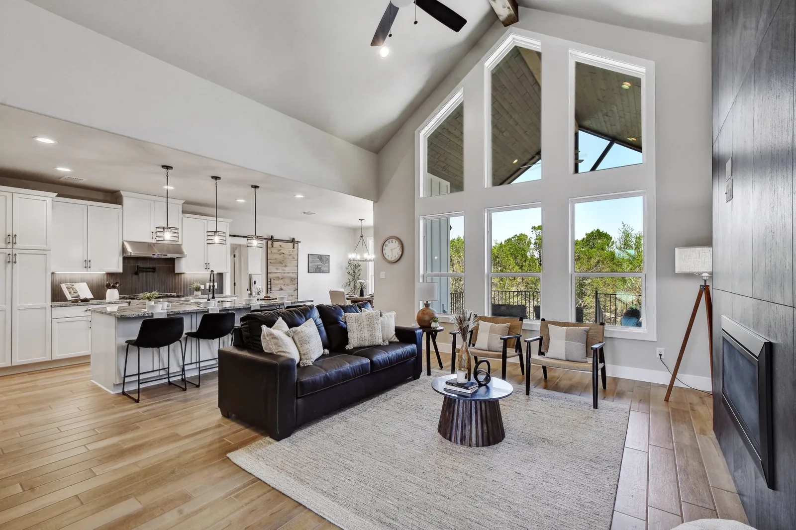 Open-plan living room and kitchen under a vaulted ceiling with tall windows