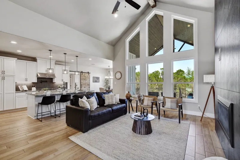 Open-plan living room and kitchen under a vaulted ceiling with tall windows