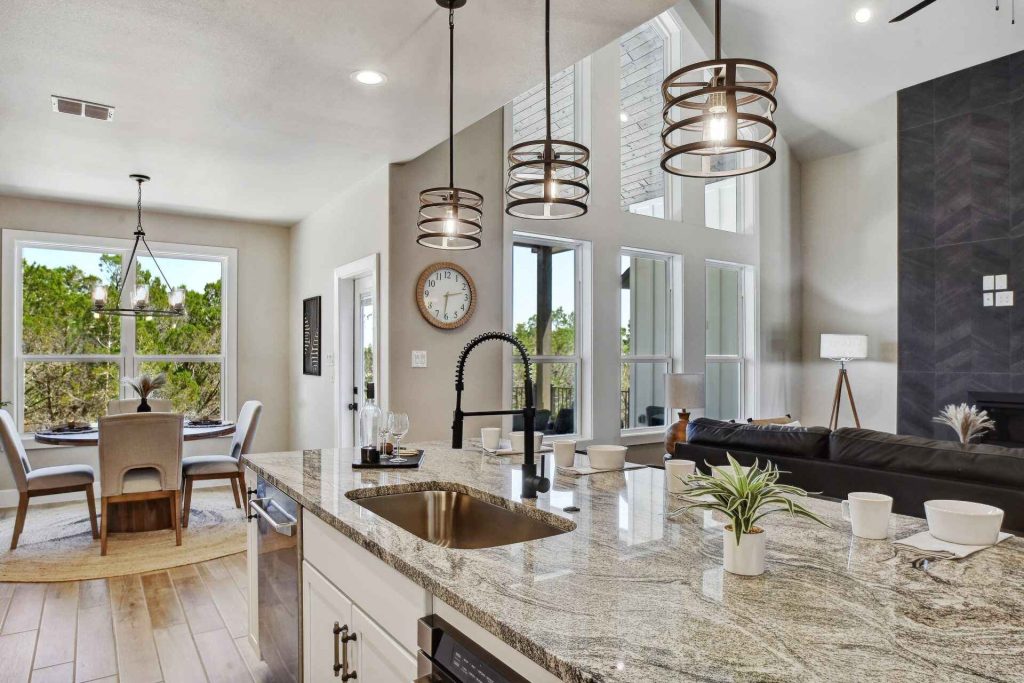 A modern kitchen featuring a sink, an island, and a cozy dining area with chairs and a table.